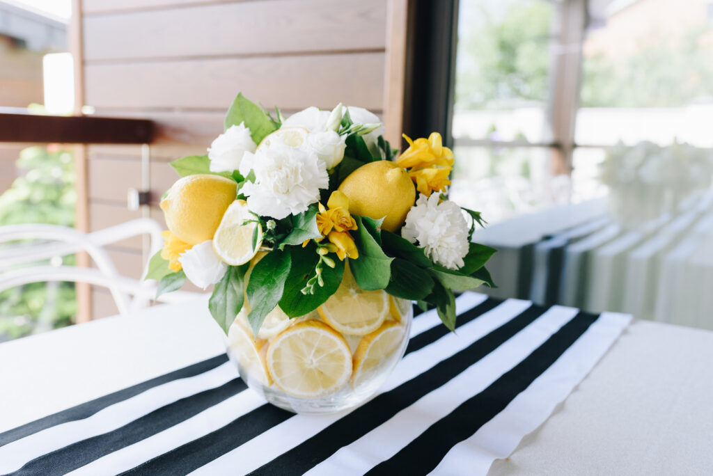 A fresh modern bouquet of white and yellow flowers and lemons for spring in a glass vase