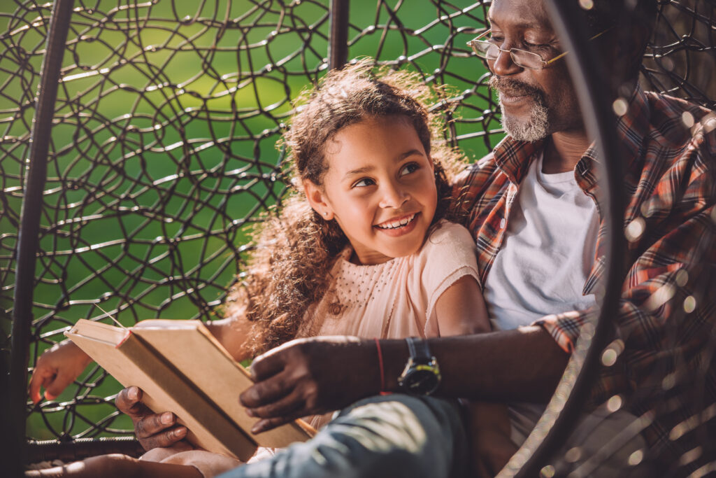 young girl reading with her grandfather in outdoor reading nook