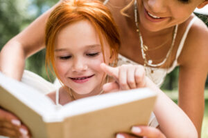 young red haired girl reading with mom working on critical thinking