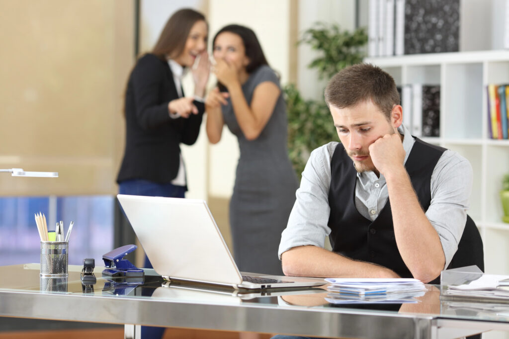 Group of coworkers joking in the workplace with negative effect on male coworker
