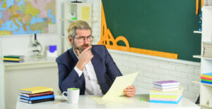 Teacher with a load of paperwork looking thoughtful