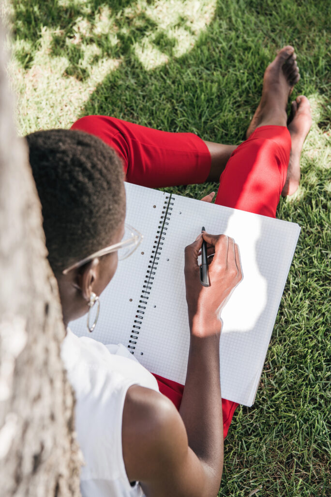 teacher journaling outdoors under tree